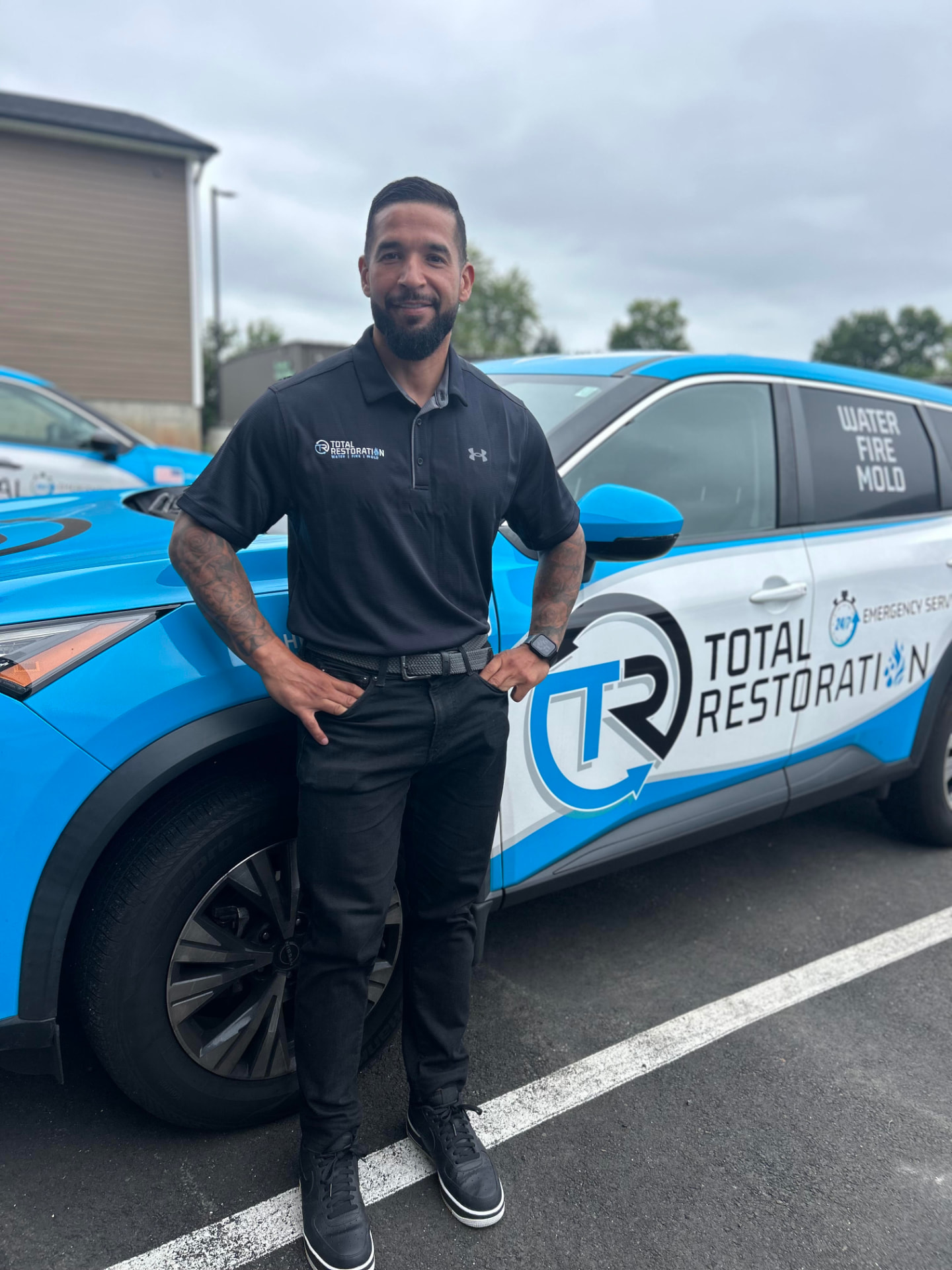 Total Restoration technician standing beside a company vehicle